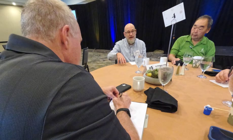 Men discussing topic around a table.