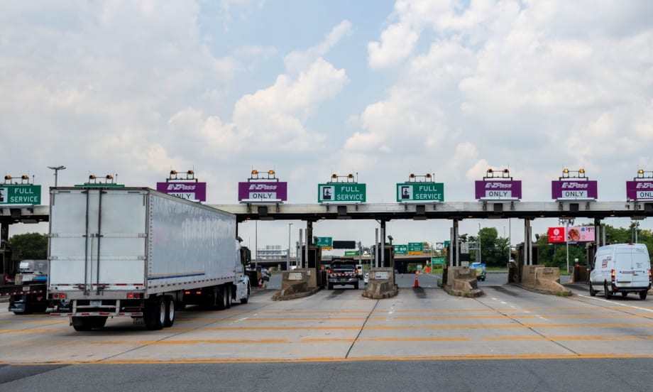 trucks and vehicles pass through a tolling plaza