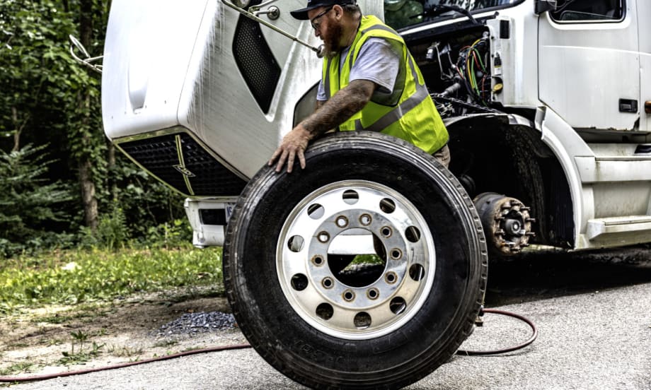 Man rolls a tire away during a roadside tire change.