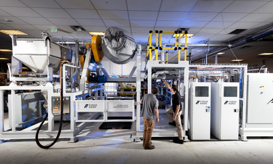 Two men stand in front of technical machinery.