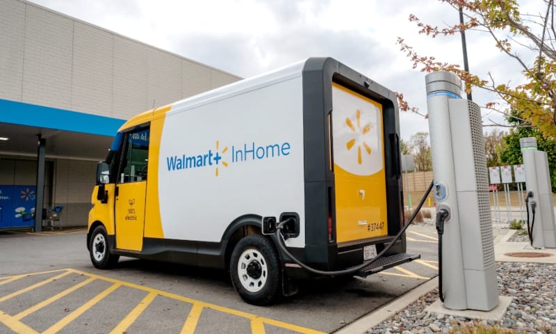 A Walmart BrightDrop battery-electric van is shown at a charging station.