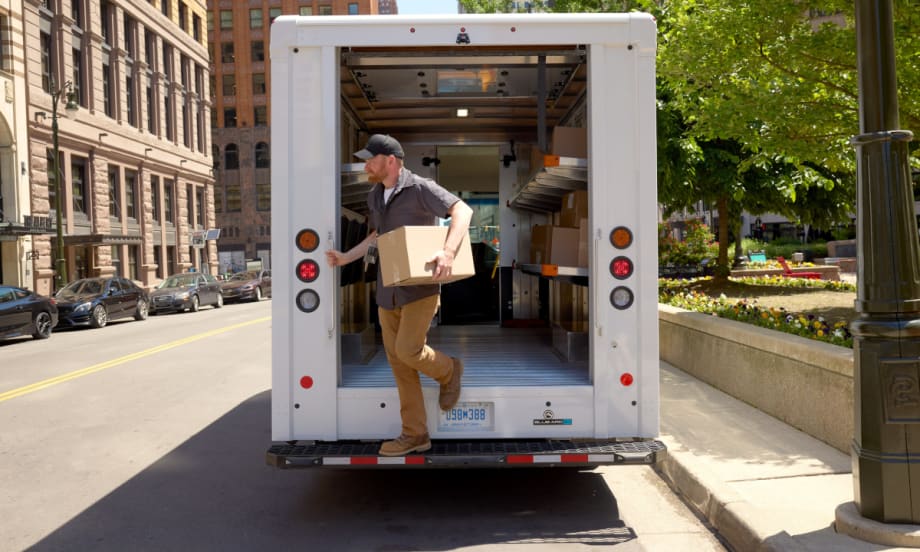 Package delivery person exits the rear of a step van.