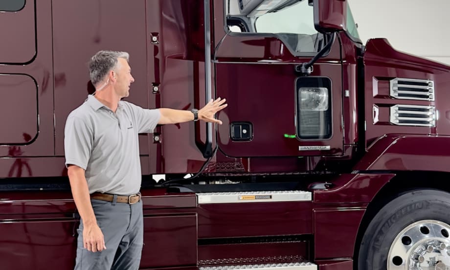 man standing in front of a Mack truck talking about it