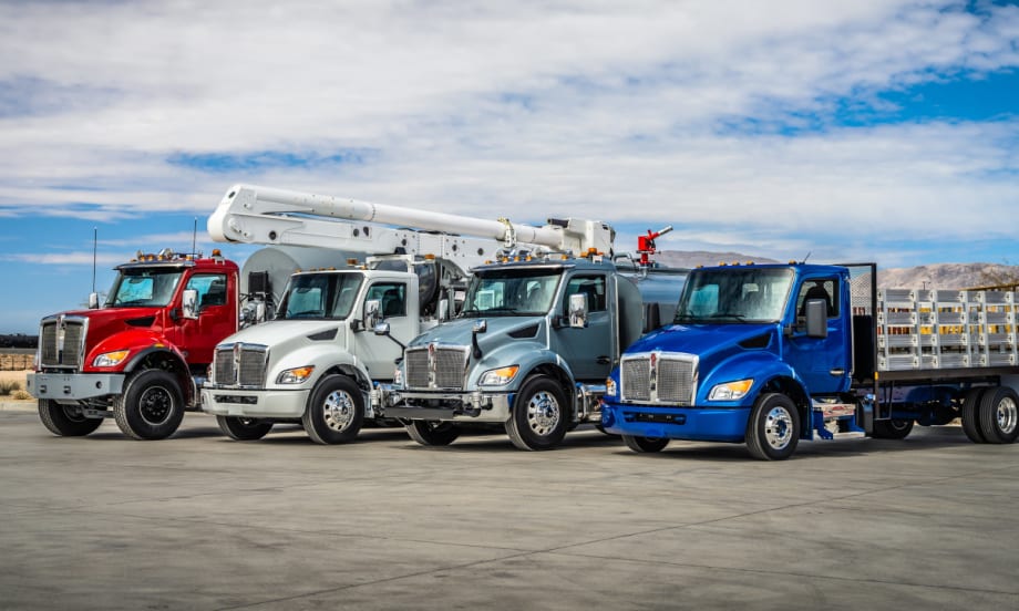 Photo of multiple medium-duty Kenworth trucks parked side by side.