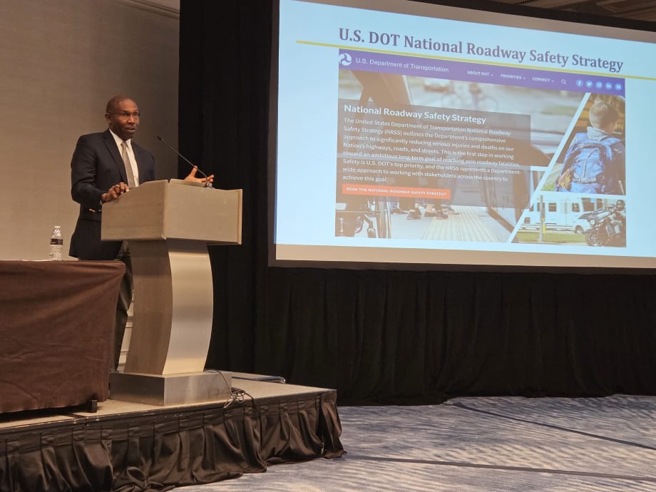 A man stands at a podium and presents to a crowd