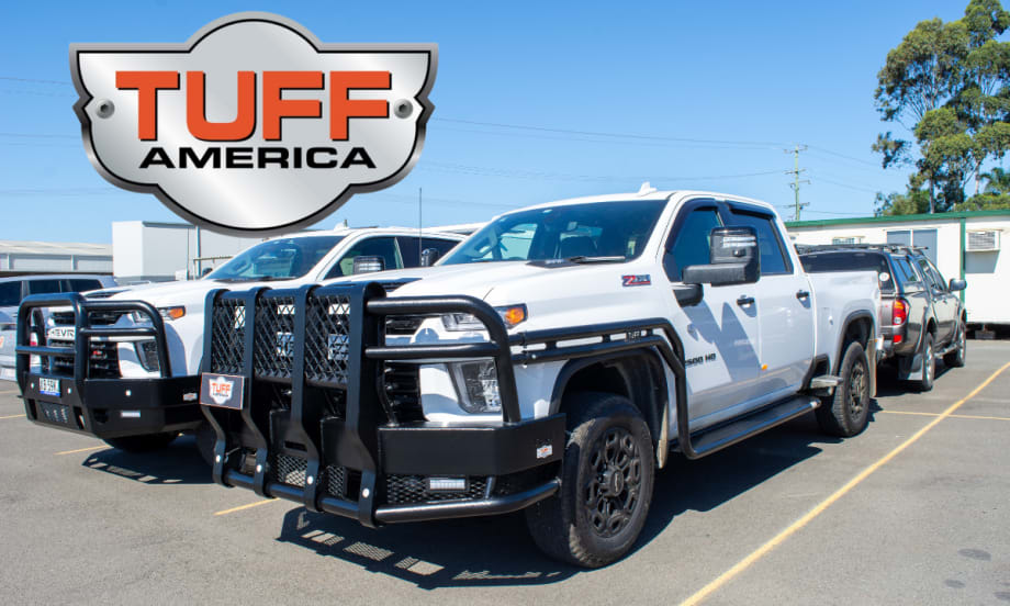 Two white pickup trucks with heavy-duty bumpers and side protection parked in a lot.