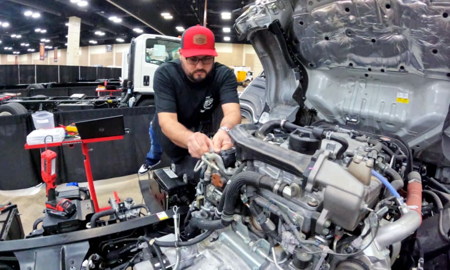 Truck technician works on the engine of a truck.