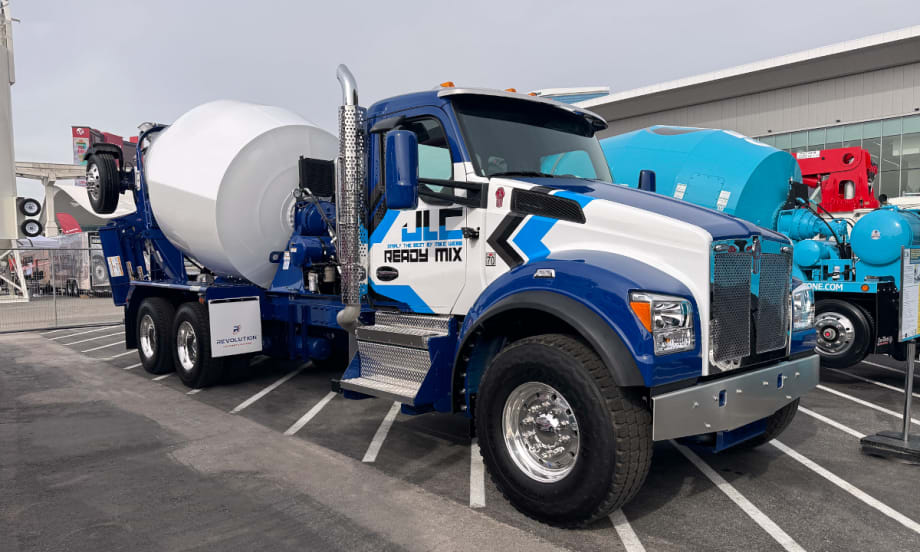 Photo of a concrete truck parked, blue and white cab, white mixer.