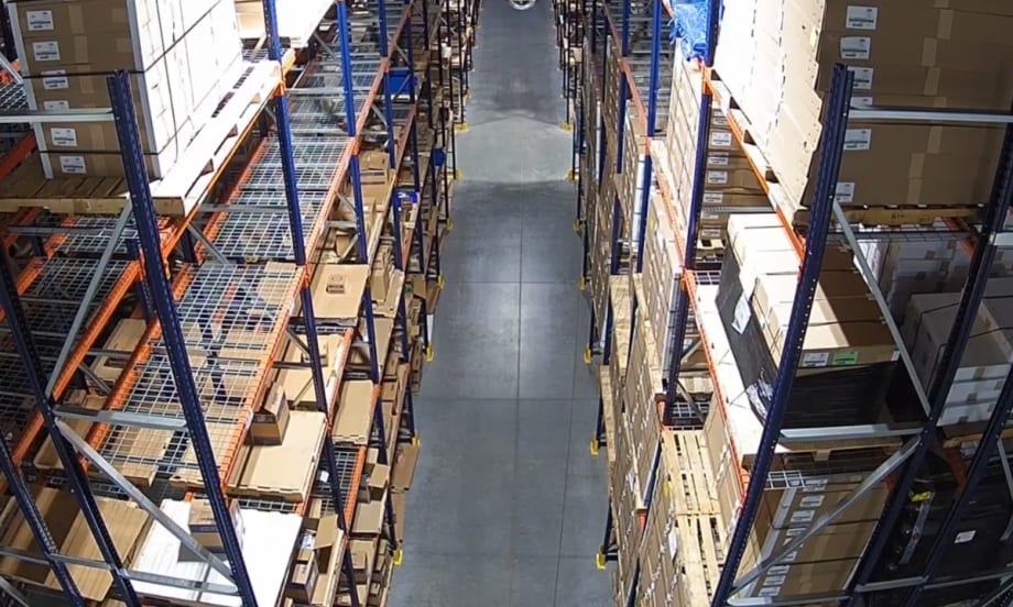 Warehouse aisle with pallet racking filled with boxed inventory at a distribution center.