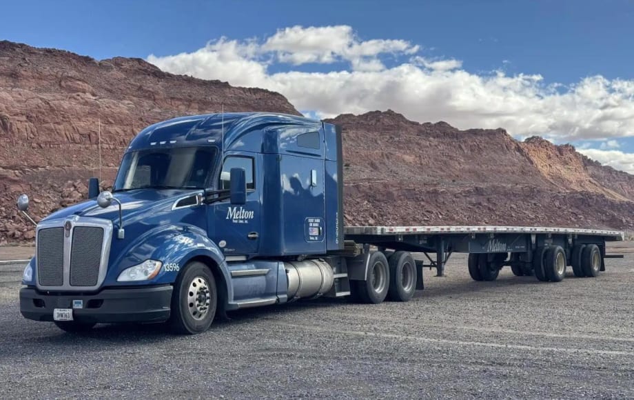 Blue heavy-duty tractor pulling a flatbed trailer