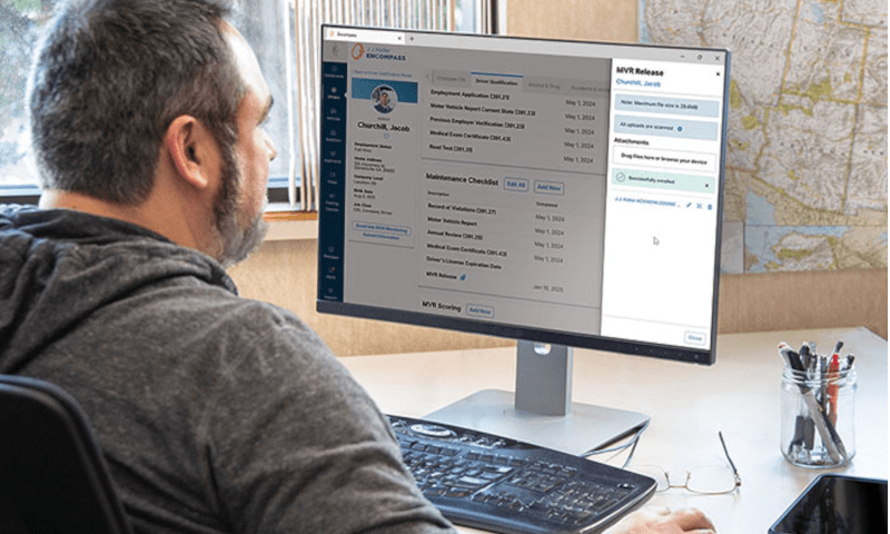 Man looks at a computer screen with reports on it.