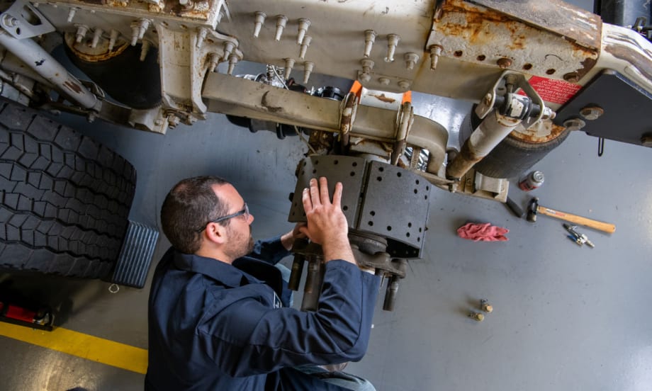 Male maintenance technician working on truck brakes.