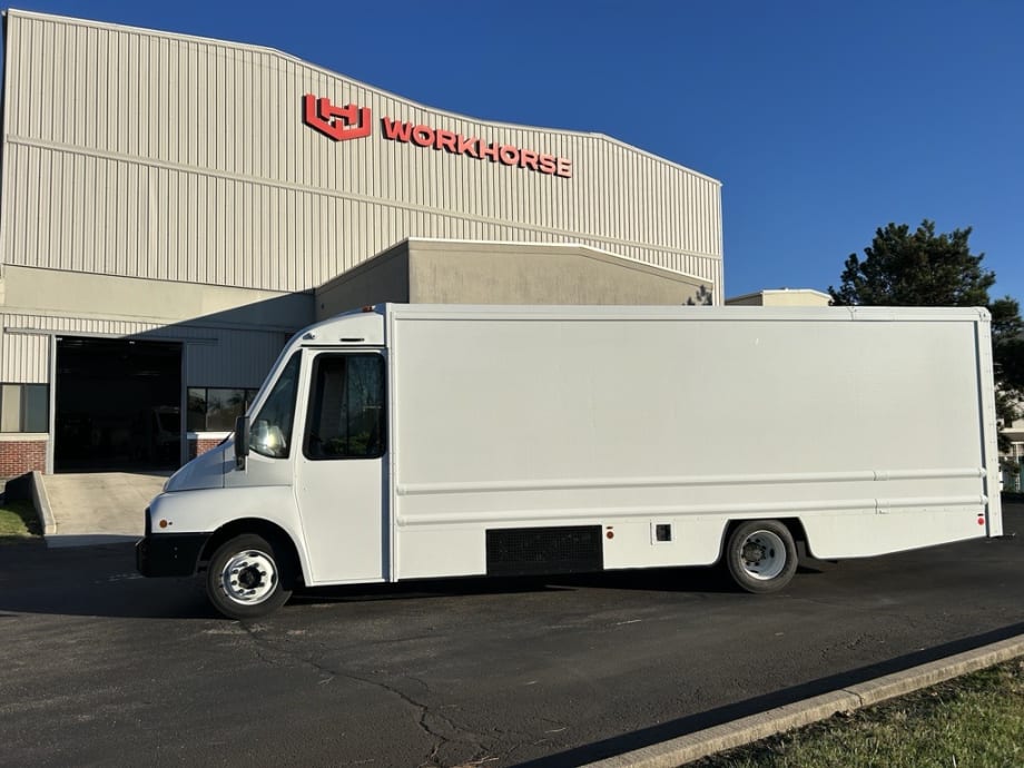 Side view of an electric step van parked in front of a building with a Workhorse sign.