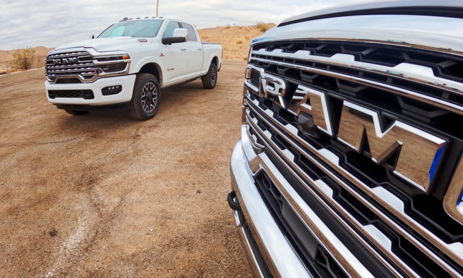 Close photo of front grille of a Ram truck, with another truck in the background