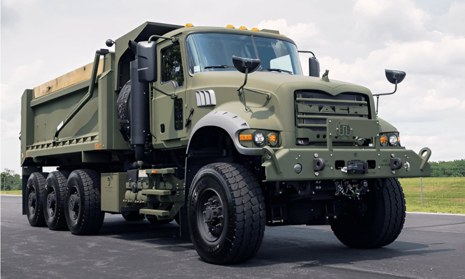 Mack military dump truck view from a low angle against a blue sky.