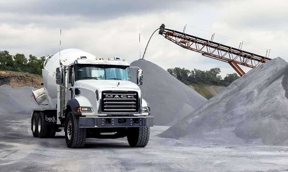 Mack concrete truck in a work setting surrounded by aggregate.