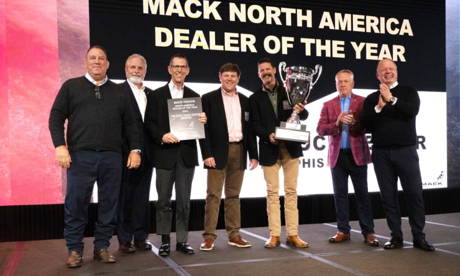 Group of businessmen on a stage presenting and receiving an award trophy.