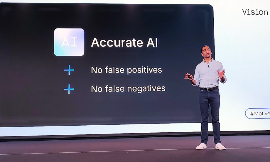 Business leader lecturing on stage in front of a protected graphic about AI.