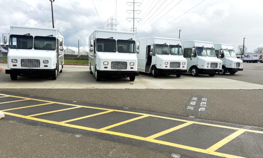 Five white step vans parked facing the camera.