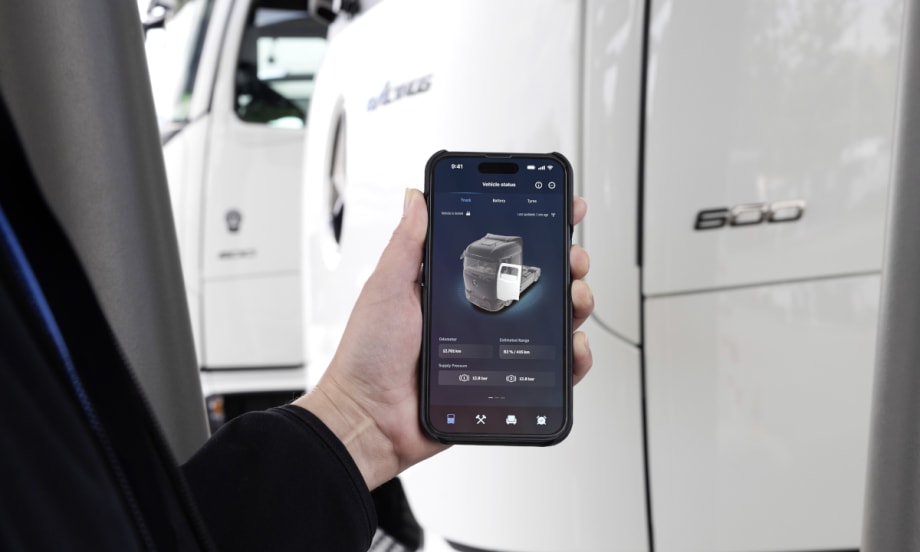 Closeup of a Mercedes-Benz app on a phone with part of a truck in the background.
