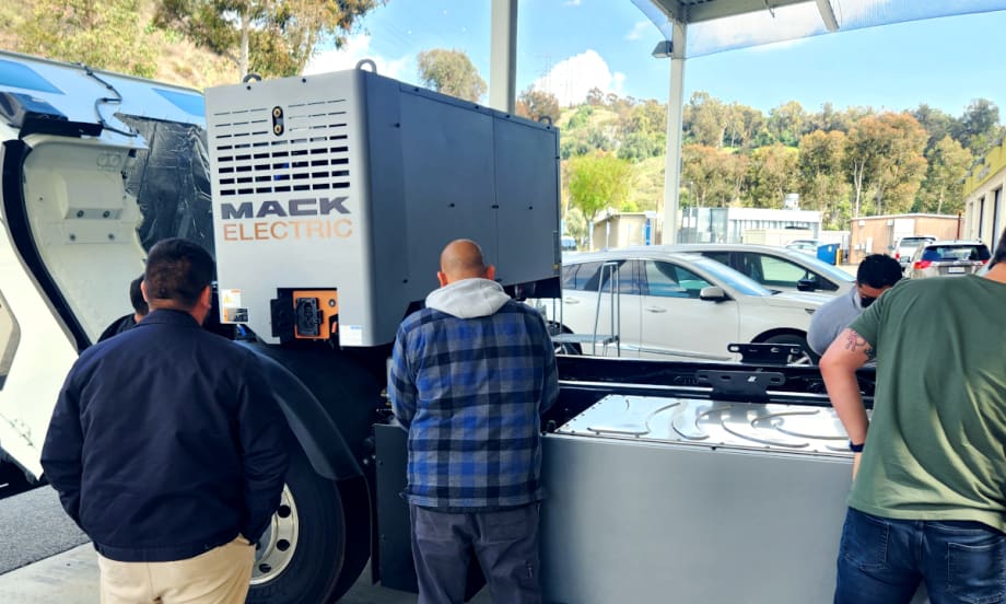Students look over a Mack LR Electric chassis.