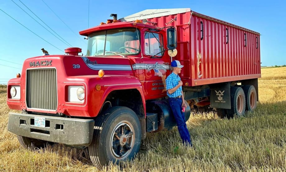 A red Mack Truck farm truck in a field.