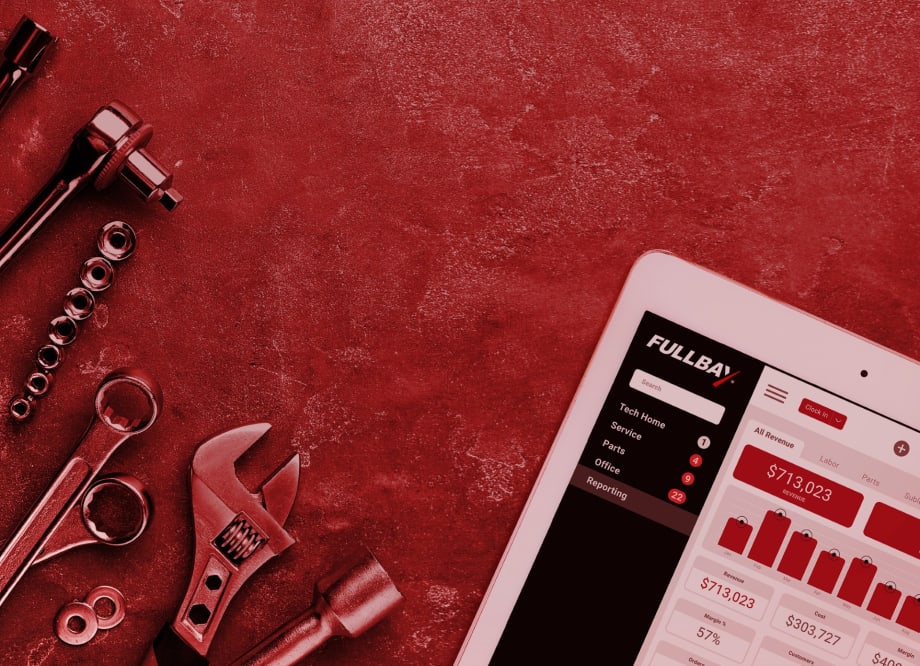 Tablet screen displaying Fullbay's repair shop management dashboard with revenue data, surrounded by hand tools on a red textured surface.