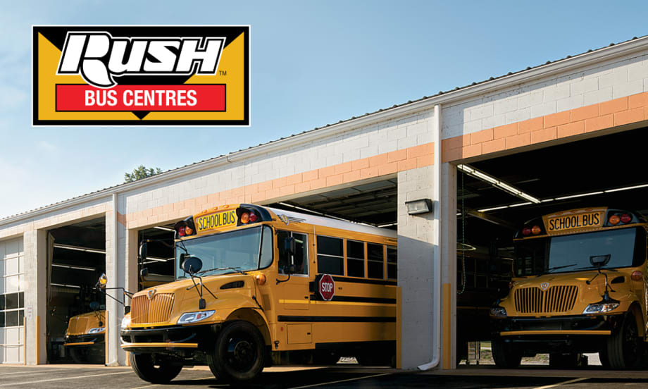 Two yellow school buses are parked in service bays at a dealership under the Rush Bus Centres logo.