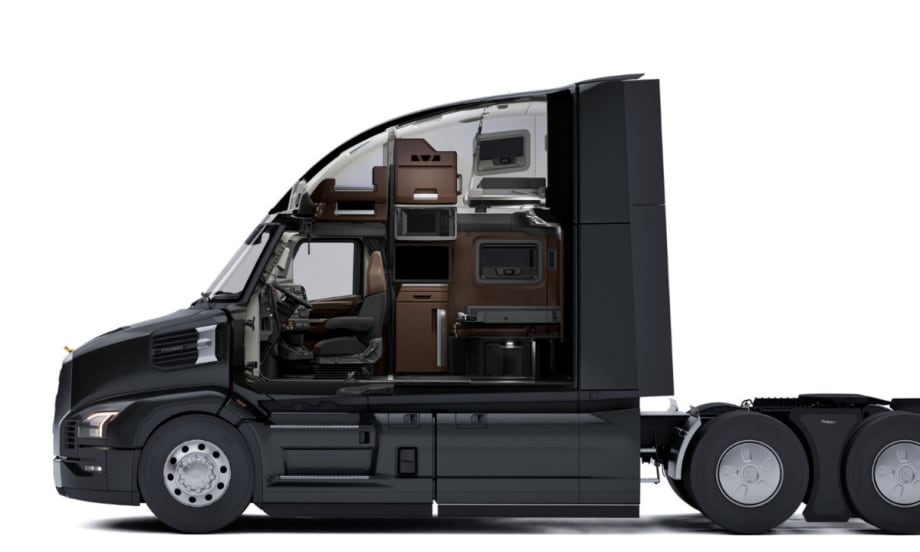 Side cutaway view of a Mack Pioneer truck cab showing the driver’s seat and sleeper area with storage cabinets, microwave, bunk beds, and workspace inside the cab interior.