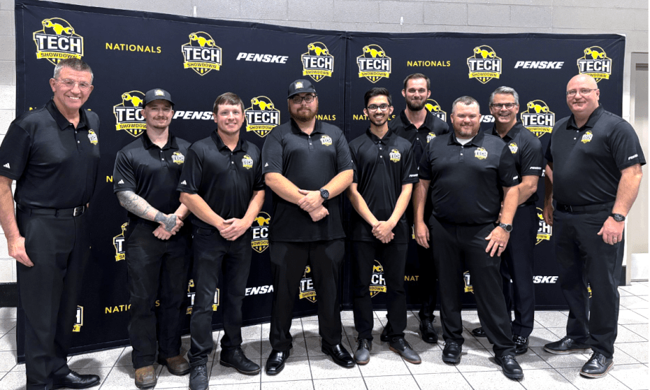 Group of men, award winners in a competition, dressed in all black standing on a stage to receive awards.