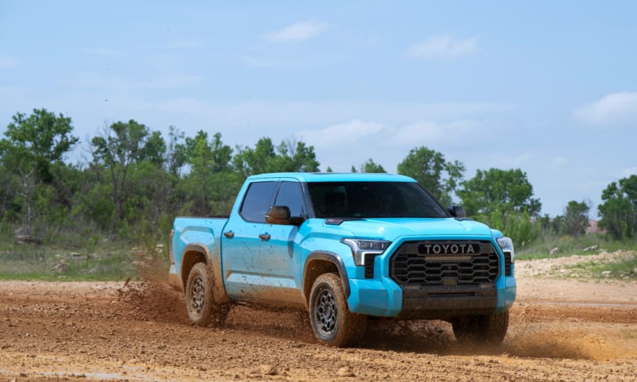 Light blue off road Toyota Tundra pickup truck driving on dirt.