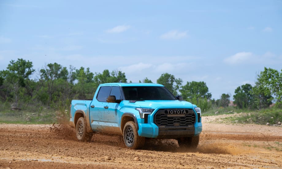 A 2026 Toyota Tundra TRD Pro in Wave Maker blue drives off-road, kicking up dirt, showcasing the truck’s off-road capability.