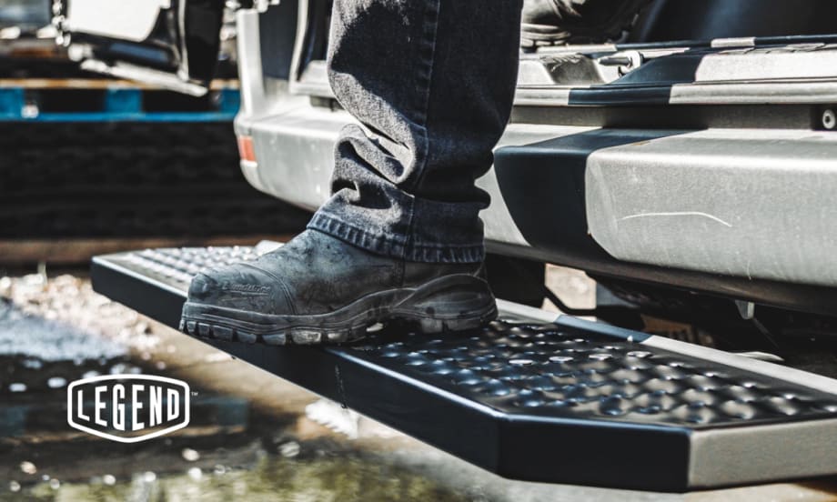 Work boot stepping onto Legend FixStep rear step with anti-slip steel tread in wet outdoor conditions, showcasing traction and durability.