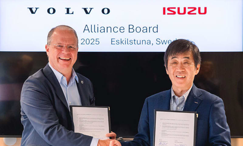 Two men in business attire shake hands after signing an agreement.