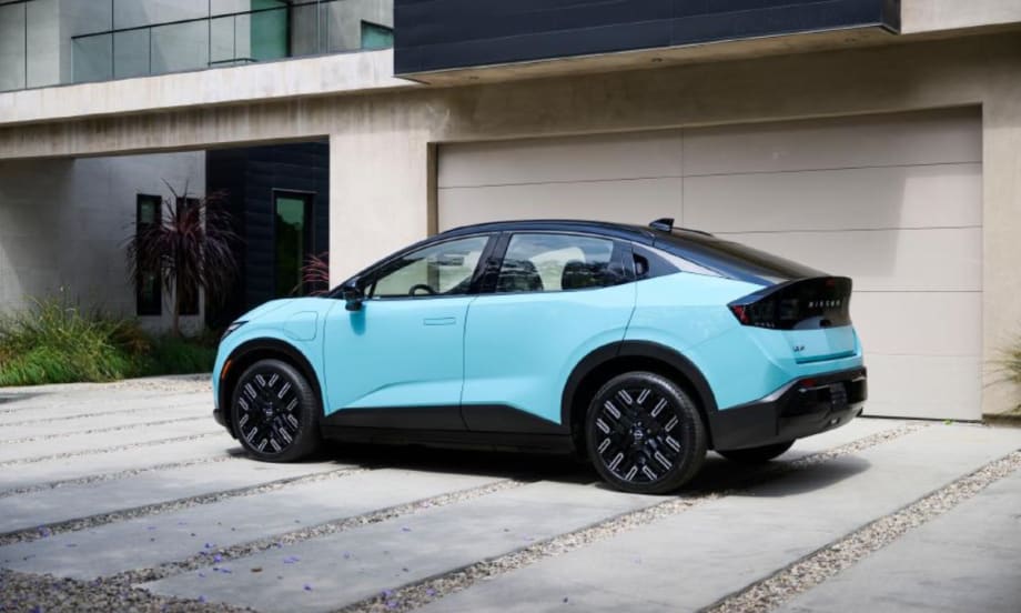 Light blue Nissan EV parked in front of a modern home garage, highlighting residential charging compatibility.