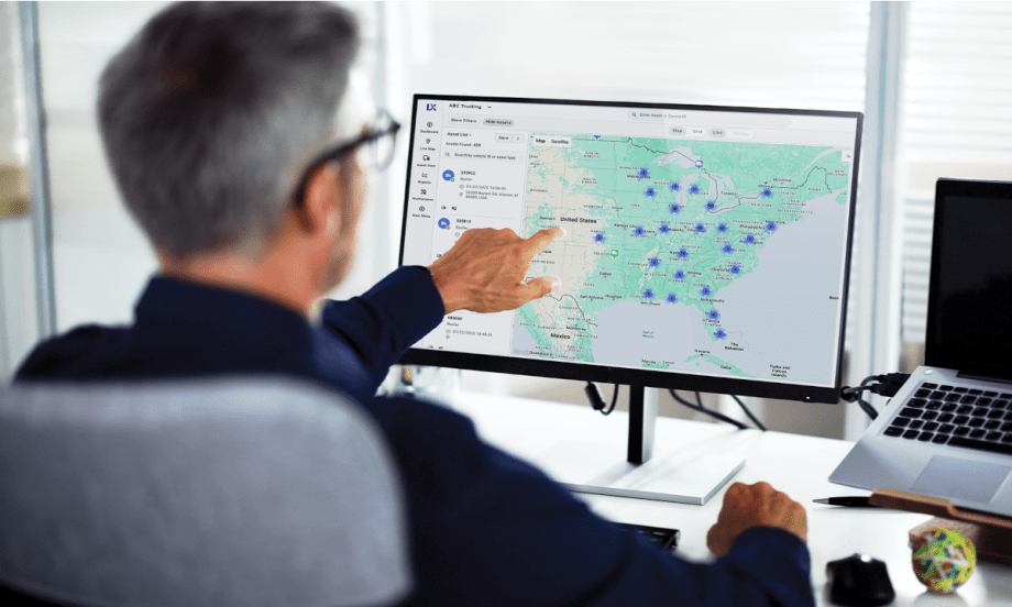 Man pointing to a map and data points on a computer screen.