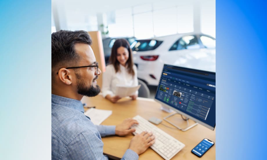 A car dealership employee uses Dealer Wizard’s equity-mining platform on a desktop computer while a customer reviews paperwork in the background.