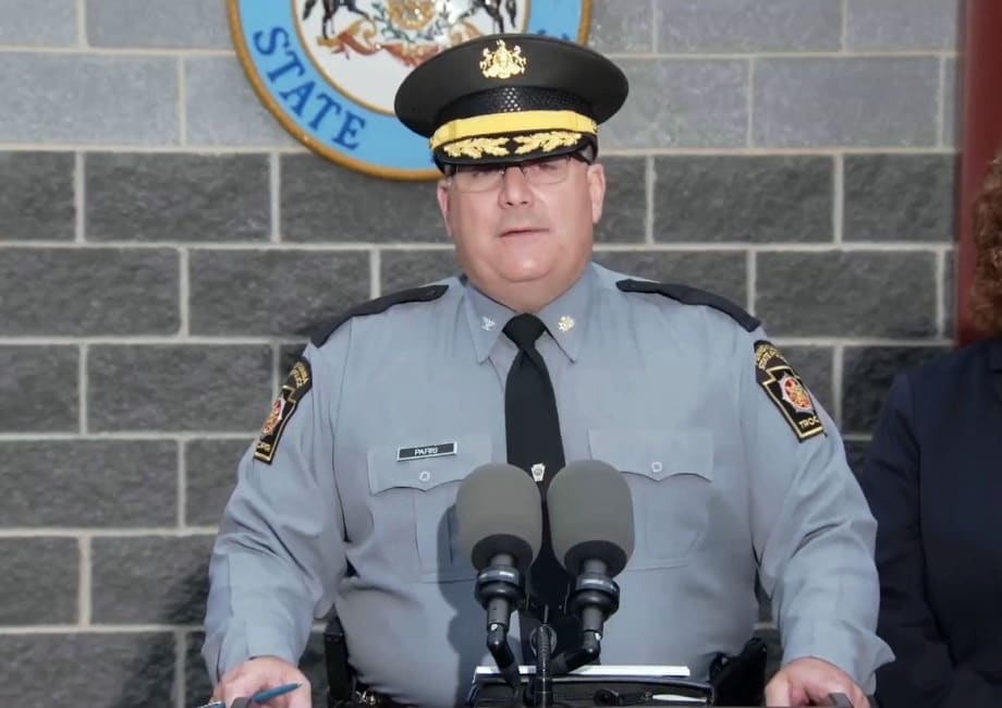 Pennsylvania State Police officer speaking at podium with official seal behind