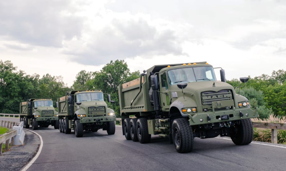 Three military dump trucks driving on a test track.