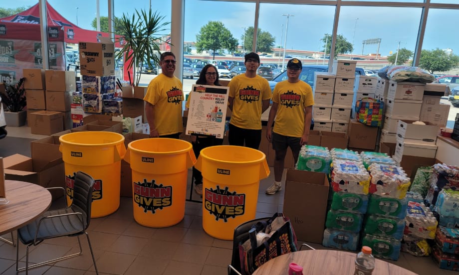 Gunn Auto Group volunteers stand with collection bins and donated supplies for the Help the Hill Country relief drive after devastating floods in Central Texas.