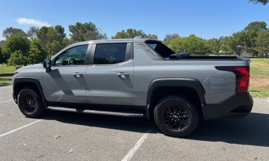A gray Chevrolet Silverado electric pickup truck in the parking lot of a public park.