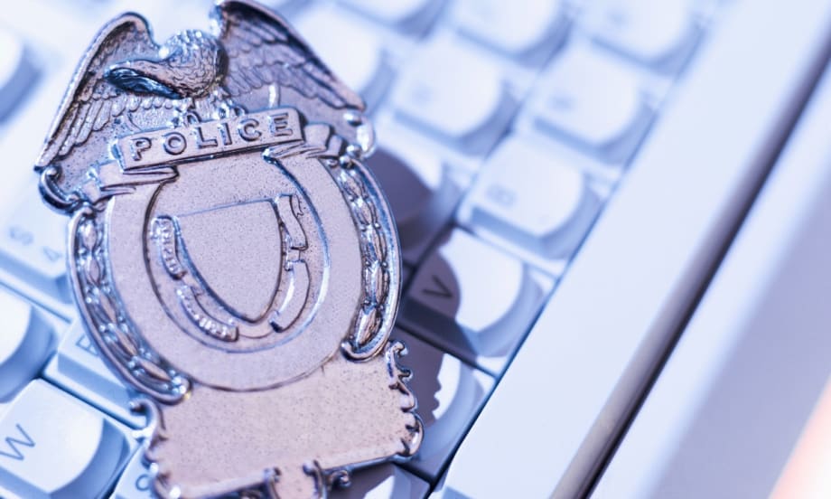 Silver police badge with eagle emblem resting on computer keyboard