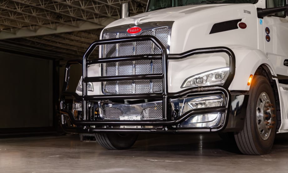 Black grille guard on front of a white tractor trailer, viewed from a front/side angle.