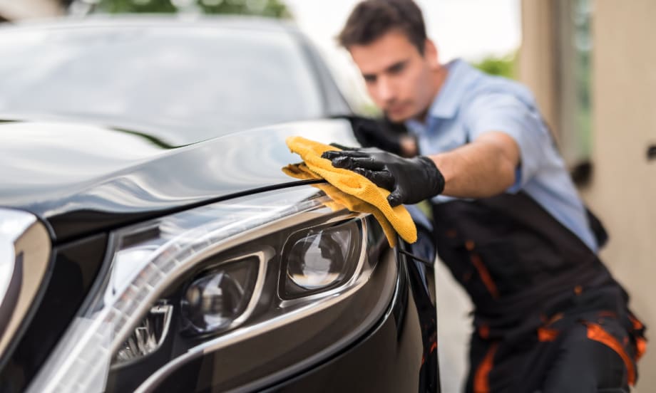 Technician polishing a car headlight with a microfiber cloth, representing Protective Asset Protection’s enhanced Appearance Protection program for long-term vehicle surface care.
