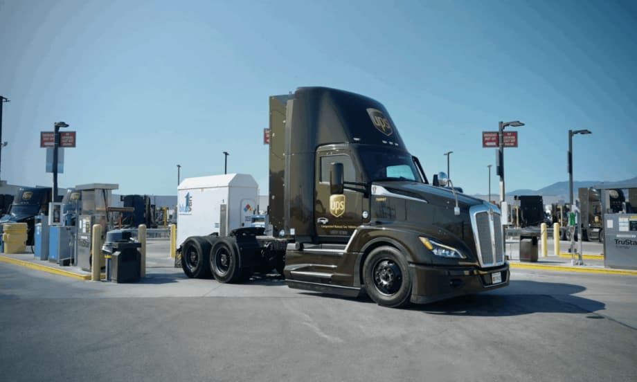 A UPS compressed natural gas (CNG) tractor is parked at a fueling station under clear skies, showcasing the company’s use of alternative fuel vehicles in its delivery fleet.