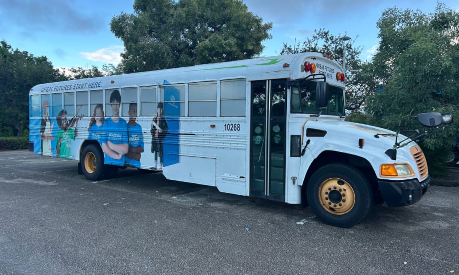 A Blue Bird Vision propane school bus operated by the Boys and Girls Club of Martin County, featuring exterior graphics of students and the slogan “Great Futures Start Here,” parked in a Florida lot.