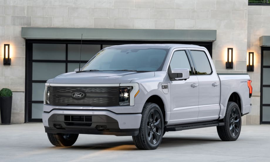 Silver Ford pickup truck parked in driveway of home in front of garage door.