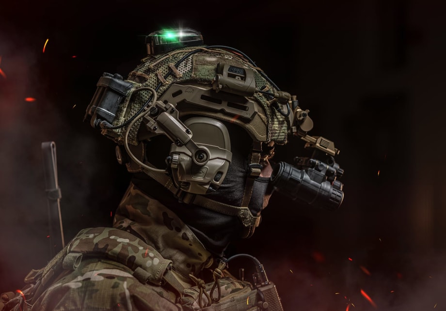 side view of a ballistic helmet in studio setting, black background, with sparks and smoke