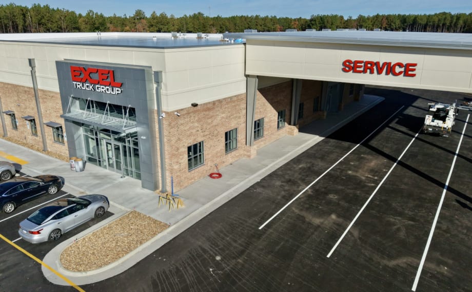 Slightly overhead view of a new truck dealership with one overhang labeled Service.