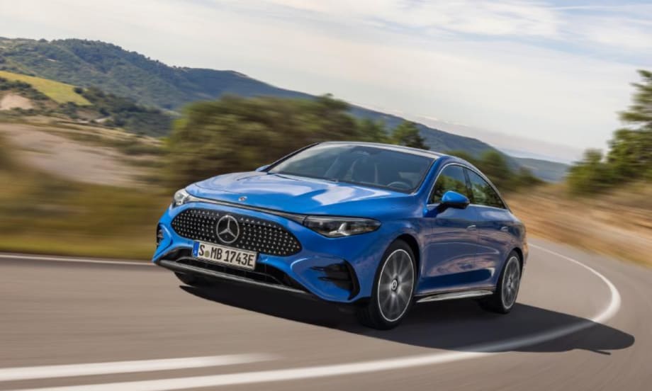 Blue Mercedes-Benz sedan driving on a curving road with blurred hills in the background.